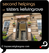 Top Secret Quote Bubble in black, with photo of blond sandstone exterior of Sisters Kelvingrove; looking up steps to entrance doorway from pavement, yellow flowers everywhere in hanging baskets and window boxes.  Caption: 'second helpings'