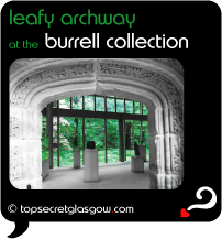 Top Secret Quote Bubble in black, with photo of interior of Burrell Collection; large arched artifact with leafy engravings built into exhibit space with other pedestals in mid distance and bright green leafy exterior beyond through glass wall. Caption: 'leafy archway'
